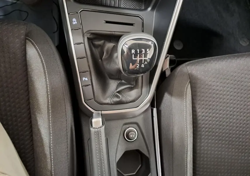 Vue plongeante sur la console centrale de la Volkswagen Polo 1.0 TSI, levier de vitesse manuel et frein à main en cuir noir.