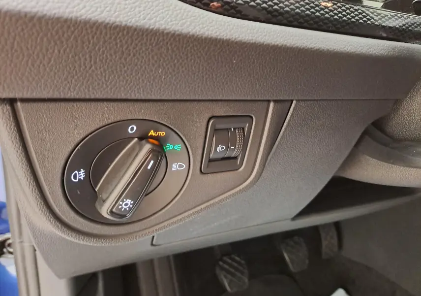Gros plan sur le bouton de commande des phares et réglage d'éclairage intérieur dans l'habitacle gris du Volkswagen Polo Bleu Récif.