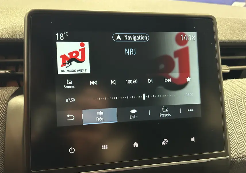 Écran tactile central de la Renault Clio V gris Rafale, affichant la radio NRJ et la navigation à 14h18.