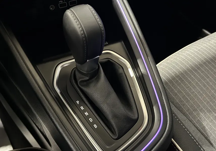 Le levier de vitesses automatique noir de la Renault Clio V E-Tech, avec éclairage d'ambiance violet et tissu gris à motifs.