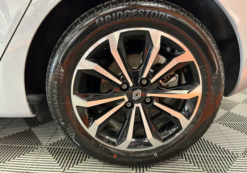 Gros plan sur la roue avant droite de la Renault Clio V gris Rafale Métal avec jante alliage bicolore et pneu Bridgestone.