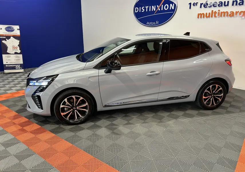 Renault Clio V E-Tech gris Rafale métal vue de profil côté gauche, avec jantes alliage et vitres teintées.