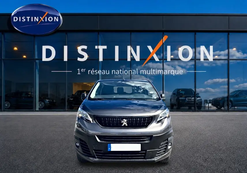 Vue de face du Peugeot Expert Fourgon gris 2024, devant une vitrine avec logo Distinxion en arrière-plan.