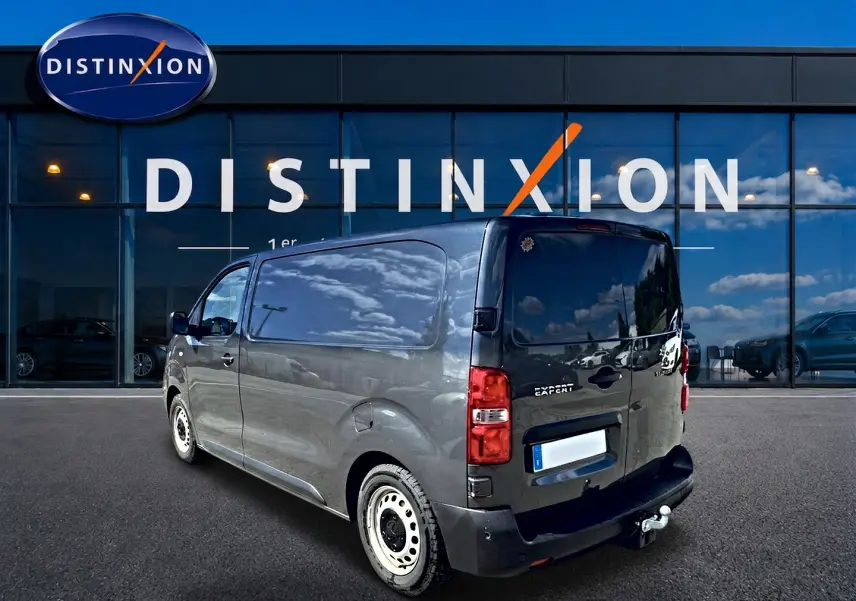 Vue 3/4 arrière droite du Peugeot Expert Fourgon gris 2024 avec porte latérale coulissante et attelage visible.
