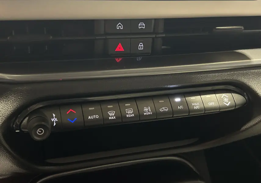 Panneau de commandes climatisation et audio de la FIAT 600 Hybrid 2024, boutons rétroéclairés sur tableau de bord noir.