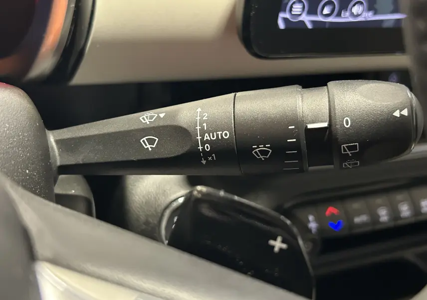 Gros plan sur la commande des essuie-glaces à gauche du volant dans le tableau de bord d'une FIAT 600 Hybrid 2024.