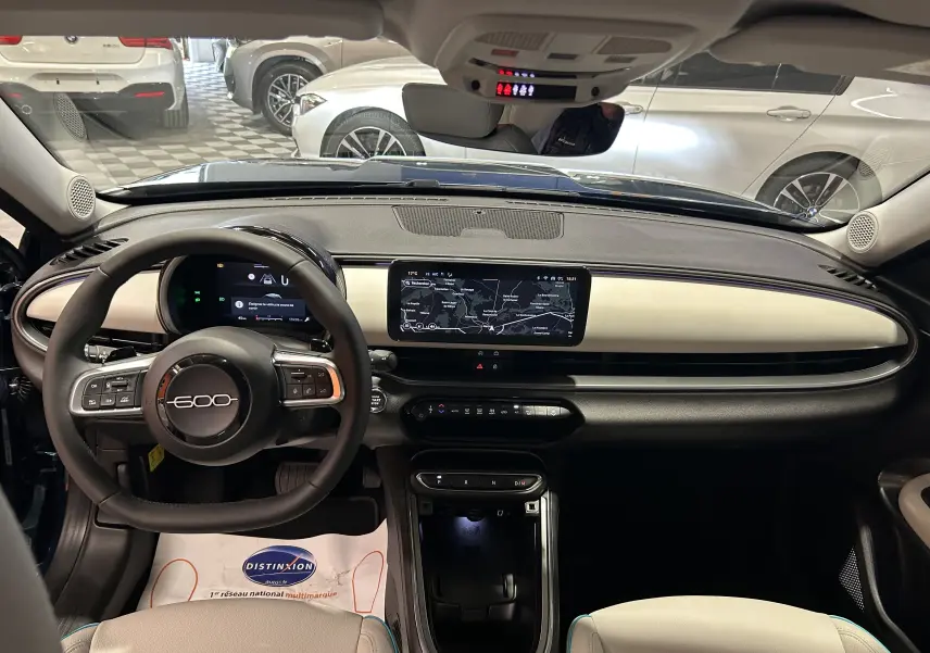 Intérieur du Fiat 600 Hybrid 2024 en bleu, vue de face sur le tableau de bord avec écran tactile et volant multifonction.
