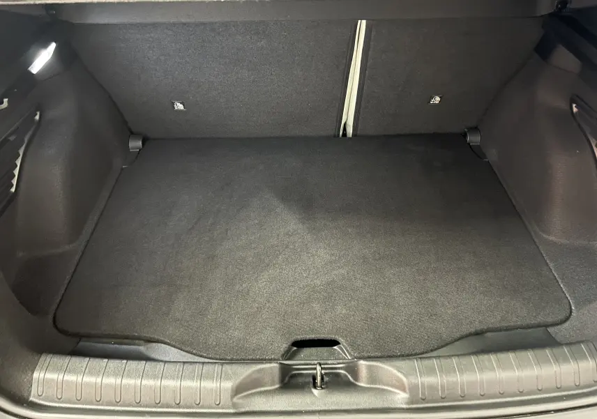 Coffre spacieux et propre de la FIAT 600 Hybrid 100 La Prima, vue arrière avec tapis noir et hayon ouvert.