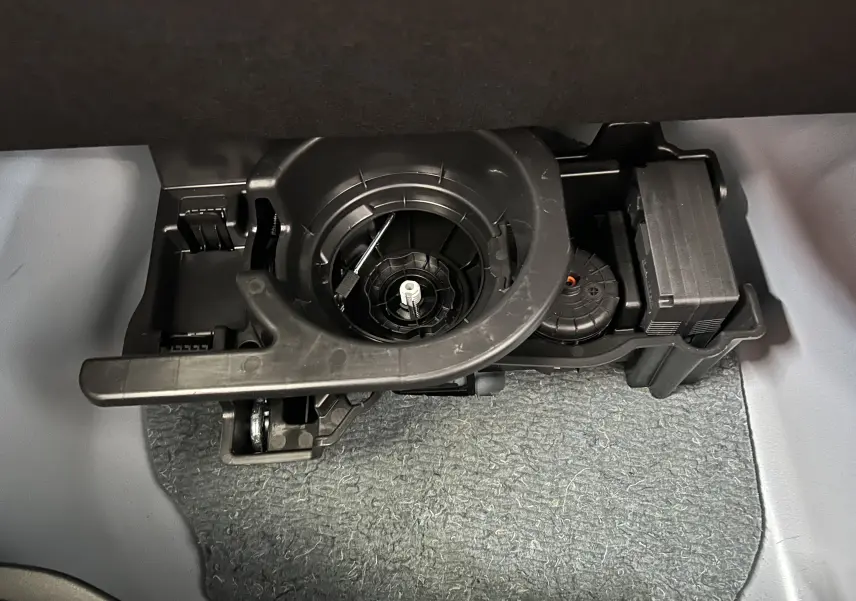 Gros plan sur le compartiment sous le plancher du coffre du FIAT 600 Hybrid 2024 montrant un outil de roue de secours.