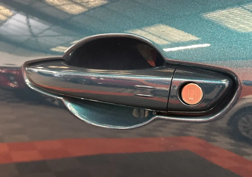 Poignée de porte bleu métallisé de la FIAT 600 Hybrid 2024 avec serrure intégrée, vue en gros plan côté droit.