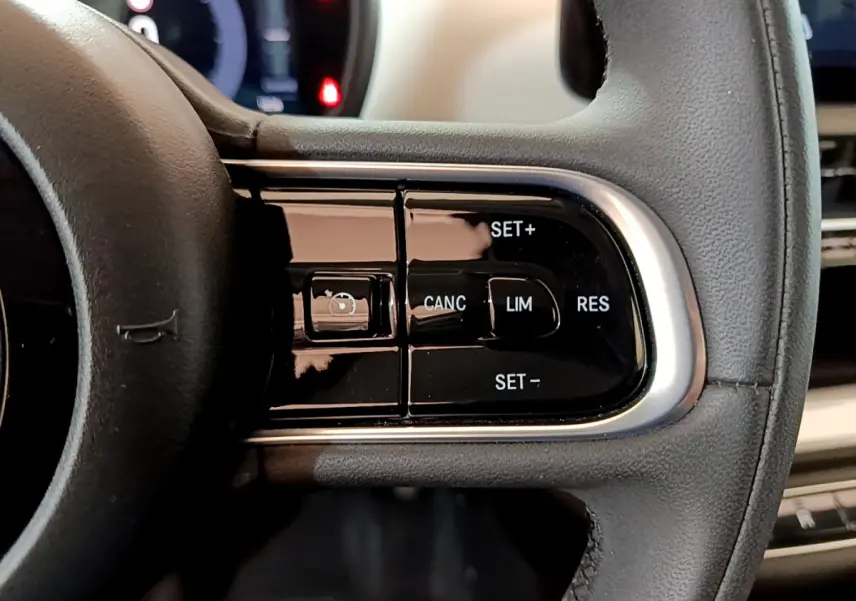 Gros plan sur les commandes du régulateur de vitesse au volant cuir noir de la Fiat 500 blanche Icône 2022.