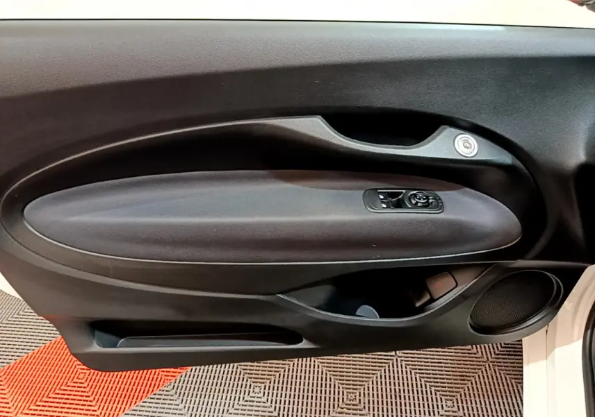 Gros plan sur la porte intérieure côté gauche d'une FIAT 500 blanche 42kWh Icône avec commandes de vitres et haut-parleur intégré.