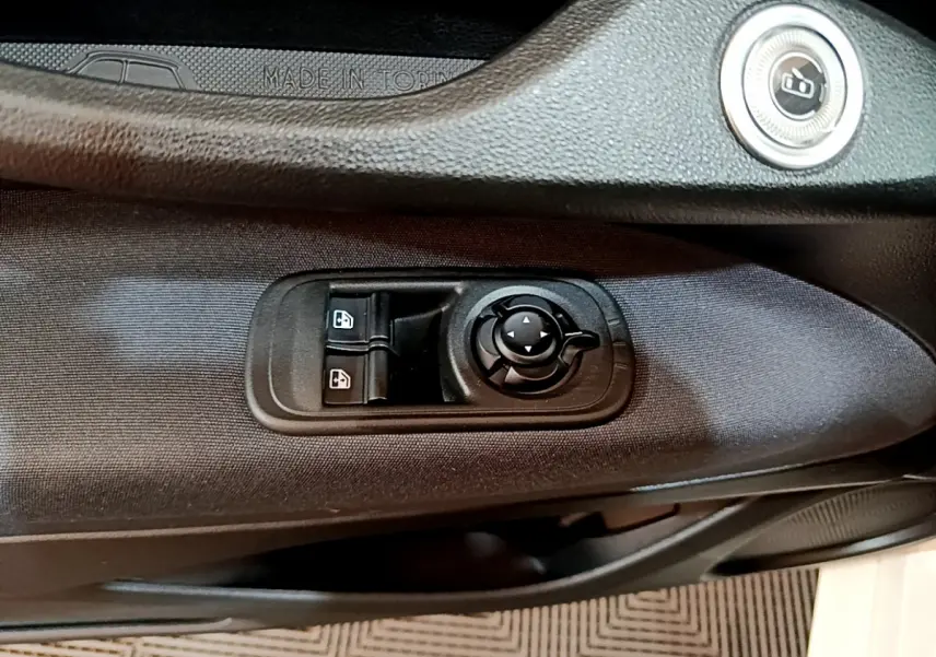 Détail des commandes de lève-vitres et réglage des rétroviseurs sur la porte côté conducteur d'une Fiat 500 blanche 2022.