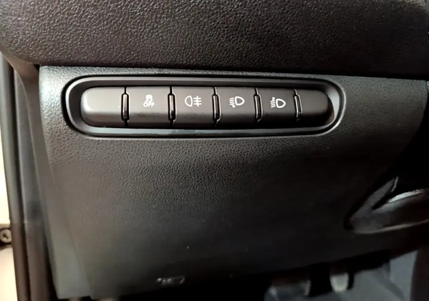 Boutons de commande des feux et de l'antipatinage sur la planche de bord noire d'une Fiat 500 blanche électrique 2022.