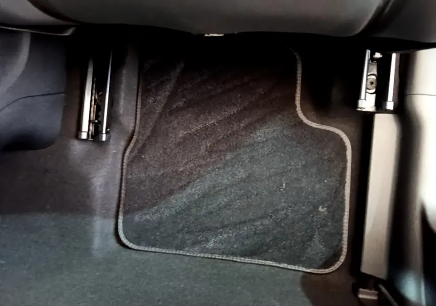 Vue rapprochée du pédalier côté conducteur de la Fiat 500 électrique blanche, avec tapis de sol noir.