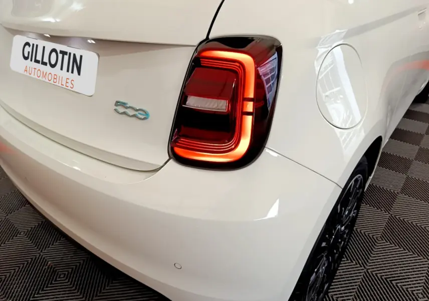 Gros plan sur l'arrière droit blanc d'une FIAT 500 électrique 42kWh Icône avec feu arrière LED allumé.