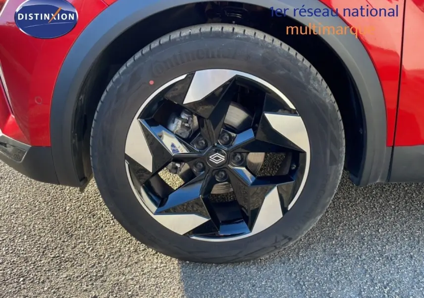 Gros plan sur la roue avant droite du Renault Captur rouge Désir Métal avec jante bi-ton noire et argentée.