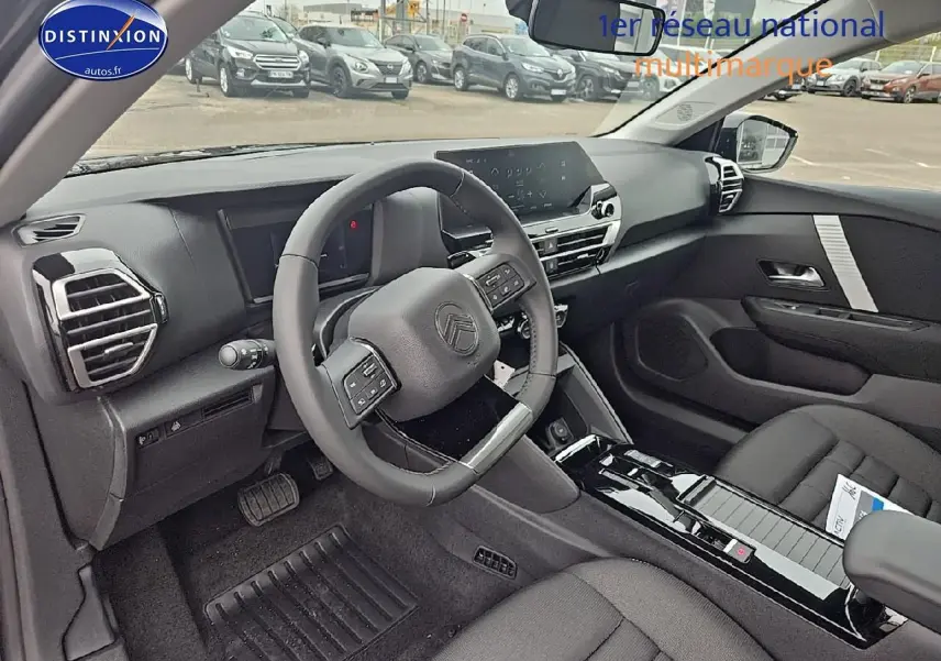 Vue intérieure côté conducteur de la Citroën C4 1.2 hybride 145 plus avec tableau de bord noir et console centrale brillante.