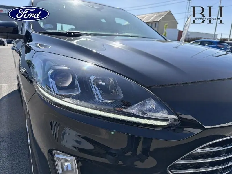 Gros plan sur le phare avant gauche du Ford Kuga 2023 noir Agate Métallisée, mettant en valeur les détails du projecteur LED.
