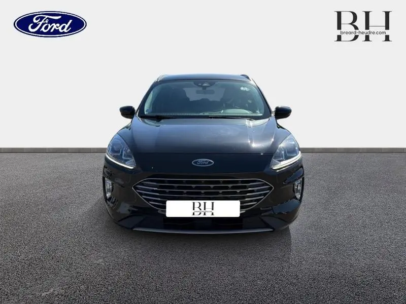 Vue avant d'un Ford Kuga noir Agate métallisé 2023 avec calandre chromée et phares LED allumés.