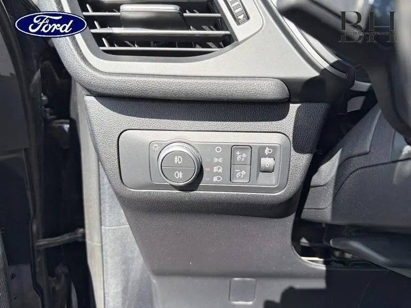 Vue rapprochée du tableau de bord côté gauche du Ford Kuga noir, montrant les commandes d'éclairage et de réglage des phares.