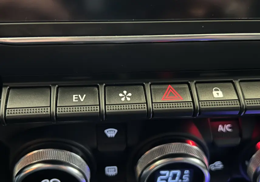 Gros plan sur les commandes centrales de la Renault Clio V E-Tech, avec boutons EV, ventilation et alerte, finition noire.