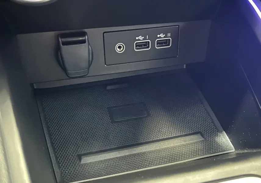Vue rapprochée de la console centrale de la Renault Clio V avec ports USB, prise jack et surface antidérapante noire.