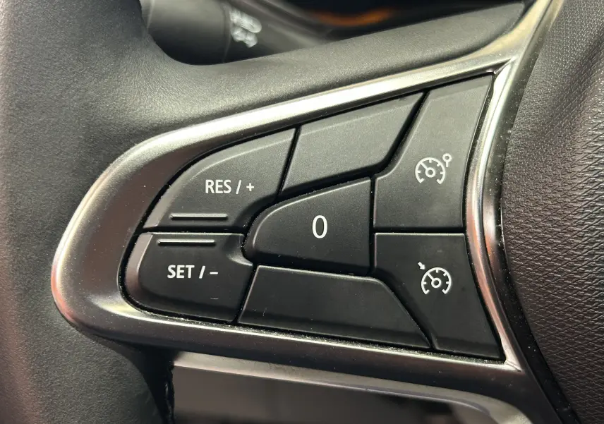Gros plan sur les commandes de régulateur de vitesse au volant d’une Renault Clio V, finition noire.