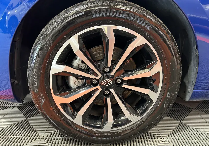 Gros plan sur la roue avant gauche de la Renault Clio V bleu Iron Metal avec jante alliage noire et argentée.