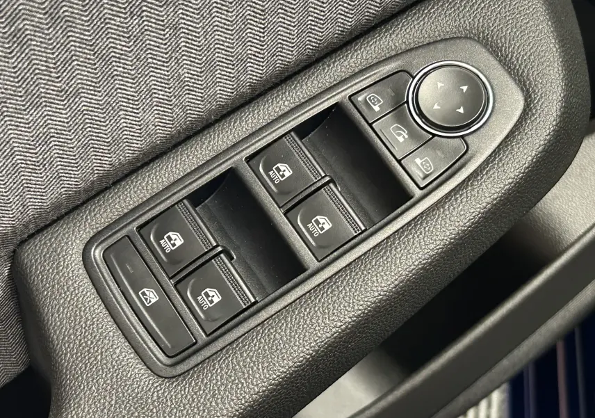 Gros plan sur les commandes de lève-vitres et rétroviseurs côté conducteur d'une Renault Clio V bleu Iron Metal.