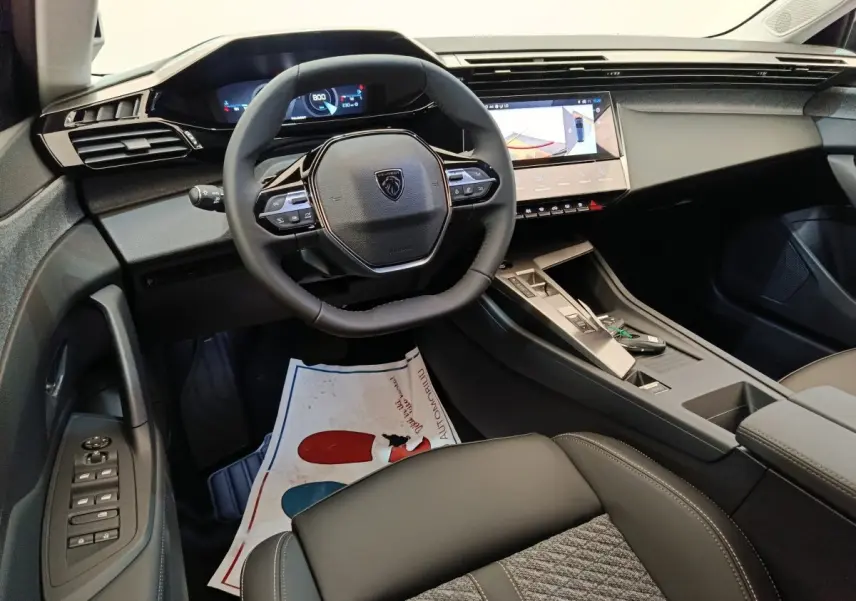 Vue intérieure côté conducteur du Peugeot 308 2026 gris foncé, volant cuir multifonctions et écran tactile central visible.