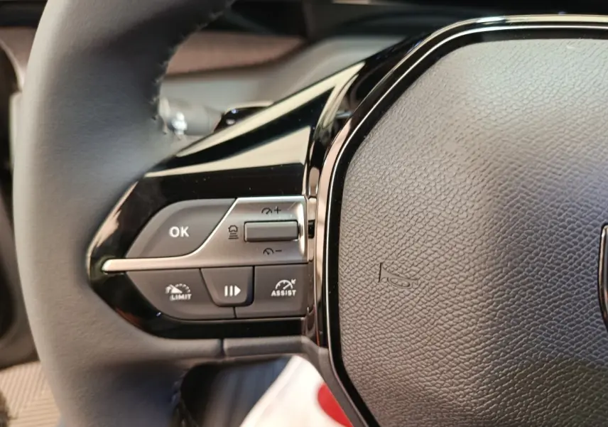Gros plan sur le côté gauche du volant cuir multifonctions de la Peugeot 308 gris foncé, avec commandes intégrées.