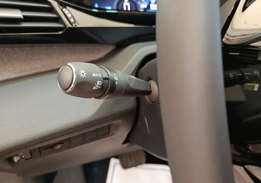 Gros plan sur la commande des phares à gauche du volant cuir dans l’habitacle de la Peugeot 308 gris foncé 2026.