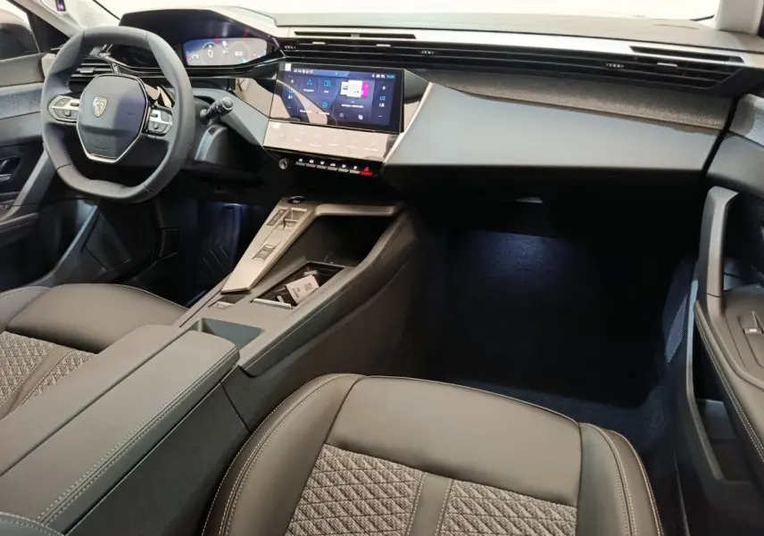 Intérieur avant de la Peugeot 308 2026, vue côté conducteur, volant cuir multifonctions et écran tactile central.