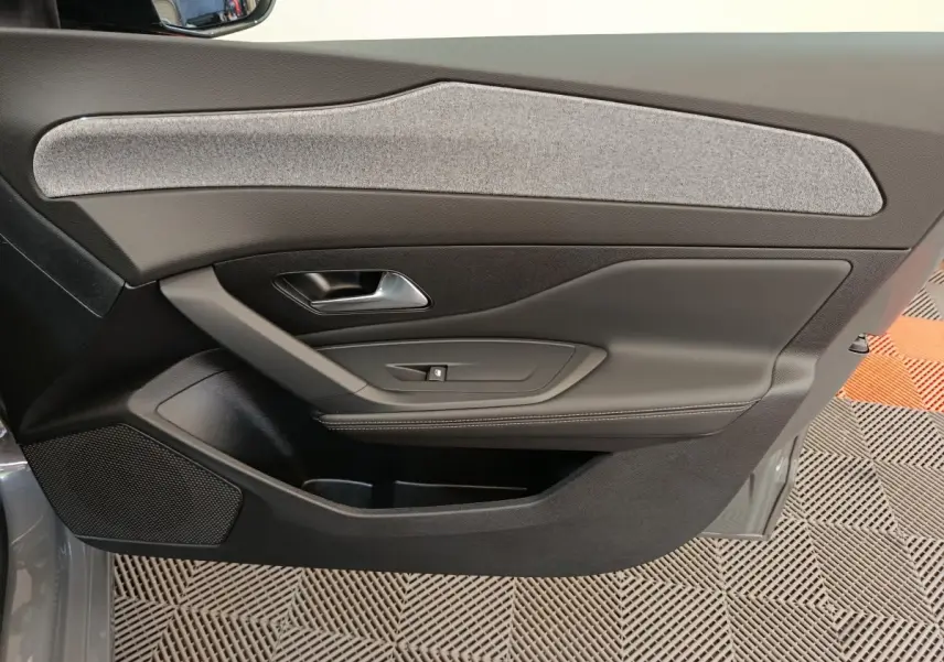 Vue rapprochée de la porte intérieure côté gauche de la Peugeot 308 gris foncé, avec garniture tissu et commandes intégrées.
