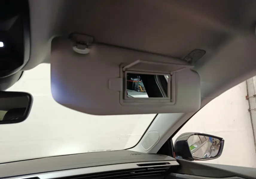 Intérieur du Peugeot 308 2026 gris foncé, vue côté passager avec pare-soleil et miroir de courtoisie ouvert.