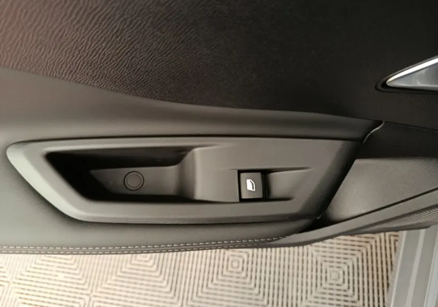Détail de la commande de lève-vitre électrique sur la porte intérieure gris foncé d’une Peugeot 308 2026.