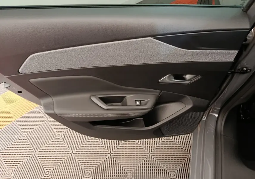 Vue intérieure de la porte avant droite gris foncé de la Peugeot 308 2026 avec habillage tissu et commandes électriques.