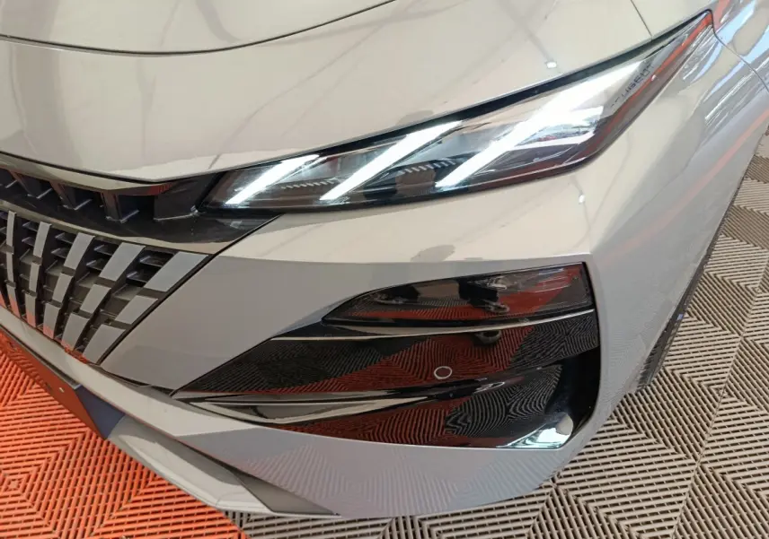 Gros plan sur l'avant droit gris foncé de la Peugeot 308 2026, mettant en valeur les phares LED et la calandre distinctive.