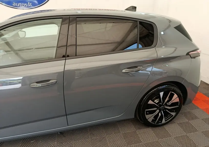 Vue latérale droite de la Peugeot 308 gris foncé avec jantes alliage noires et vitres teintées.