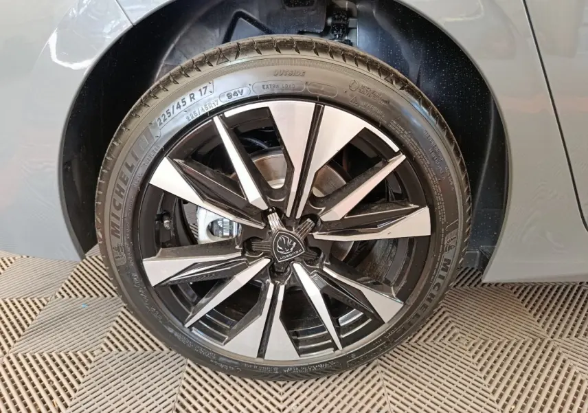 Gros plan sur la roue avant droite de la Peugeot 308 gris foncé, jante alliage noire et argentée au design moderne.