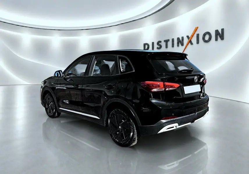 Vue 3/4 arrière droite du SUV MG ZS 1.5 hybrid noir, avec feux arrière LED et jantes noires dans un showroom lumineux.