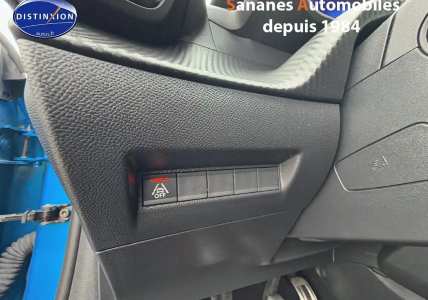 Gros plan sur la console côté gauche avec bouton désactivation assistance au maintien de voie, intérieur noir, portière bleu clair visible.