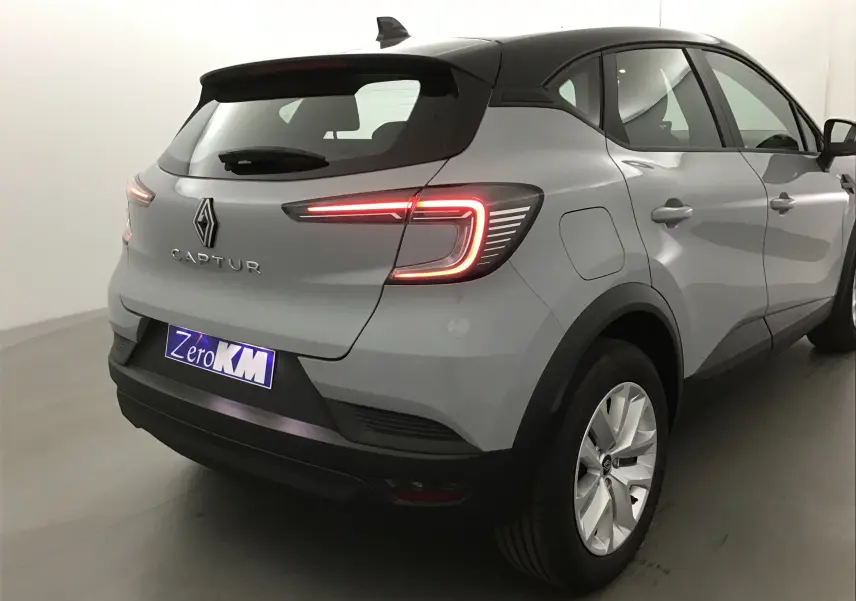 Vue 3/4 arrière droite du Renault Captur 2025 gris Rafale avec toit noir et feux arrière LED allumés.