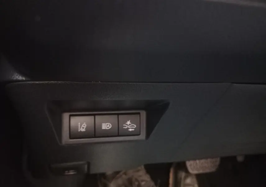 Gros plan sur les commandes de sécurité sous le tableau de bord d'une Toyota Yaris blanche hybride 2019.