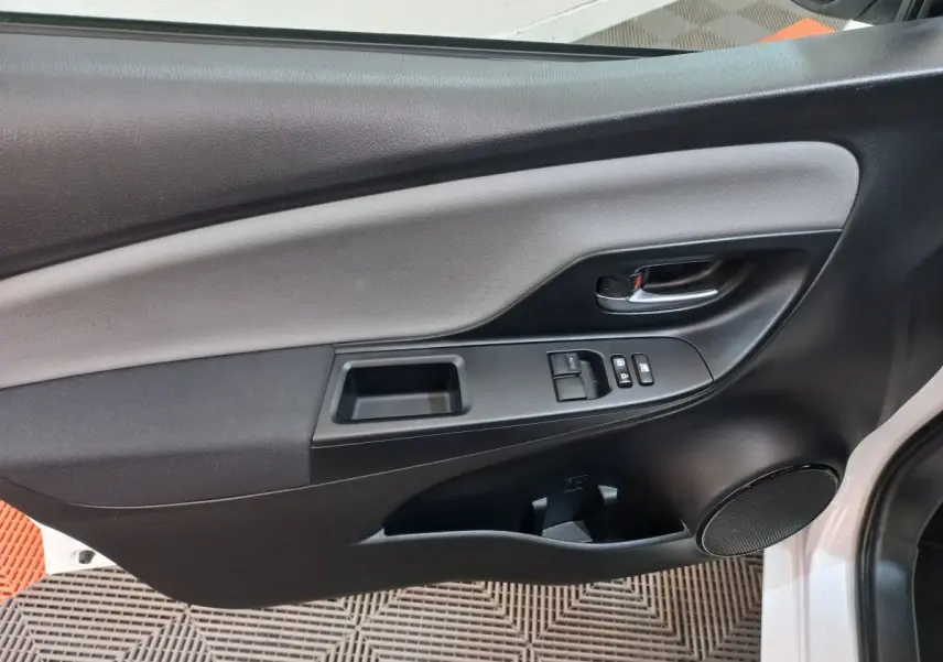 Panneau intérieur côté gauche de la porte avant d'une Toyota Yaris blanche, avec commandes de vitres et poignée chrome.