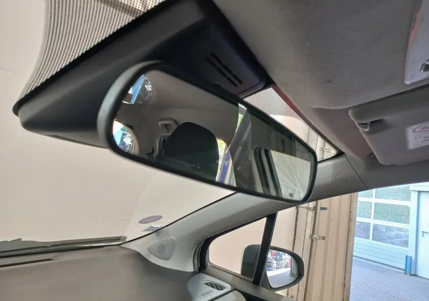 Vue intérieure du rétroviseur central d'une Toyota Yaris blanche 2019, avec partie avant droite visible et siège arrière en reflet.