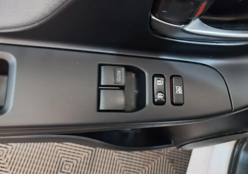 Gros plan sur les commandes de lève-vitres et verrouillage côté conducteur de la Toyota Yaris blanche 2019.