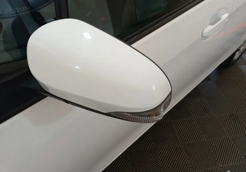 Rétroviseur côté gauche blanc avec clignotant intégré sur Toyota Yaris hybride 2019 vue rapprochée du côté conducteur.