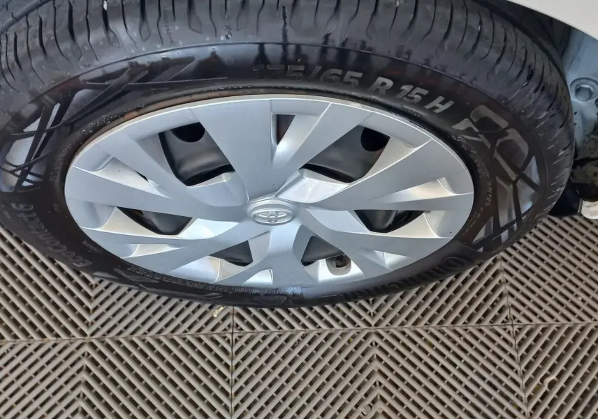 Gros plan sur la roue avant droite d'une Toyota Yaris blanche, mettant en valeur la jante argentée et le pneu Continental.